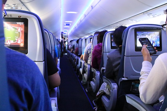 飛行機内でスマホを持つ人やたくさんの座席