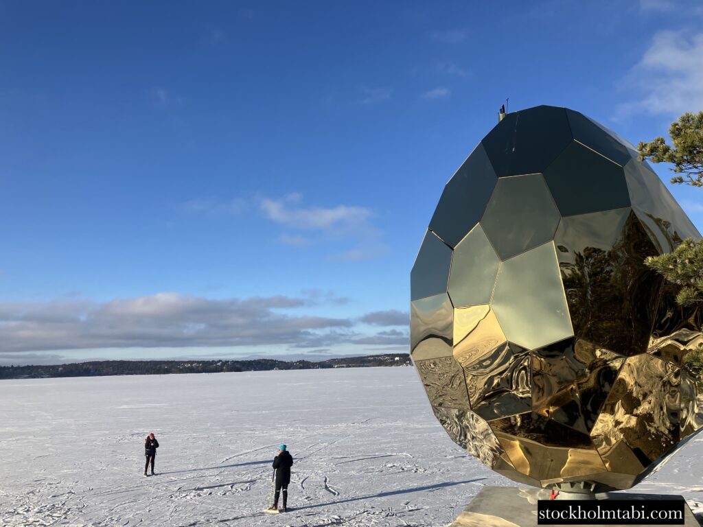 Artipelagの金色のソーラーエッグと凍った海を歩く人